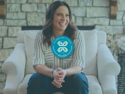 Melissa Harrison, sitting on chair in front of fireplace with Allee Creative logo