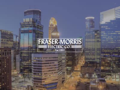 Downtown Minneapolis skyline at night with Fraser-Morris Electric Co. Logo