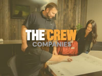 Men and women reviewing architectural plans with The Crew Companies logo