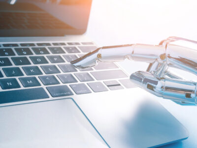 Robot hand pressing keys on laptop