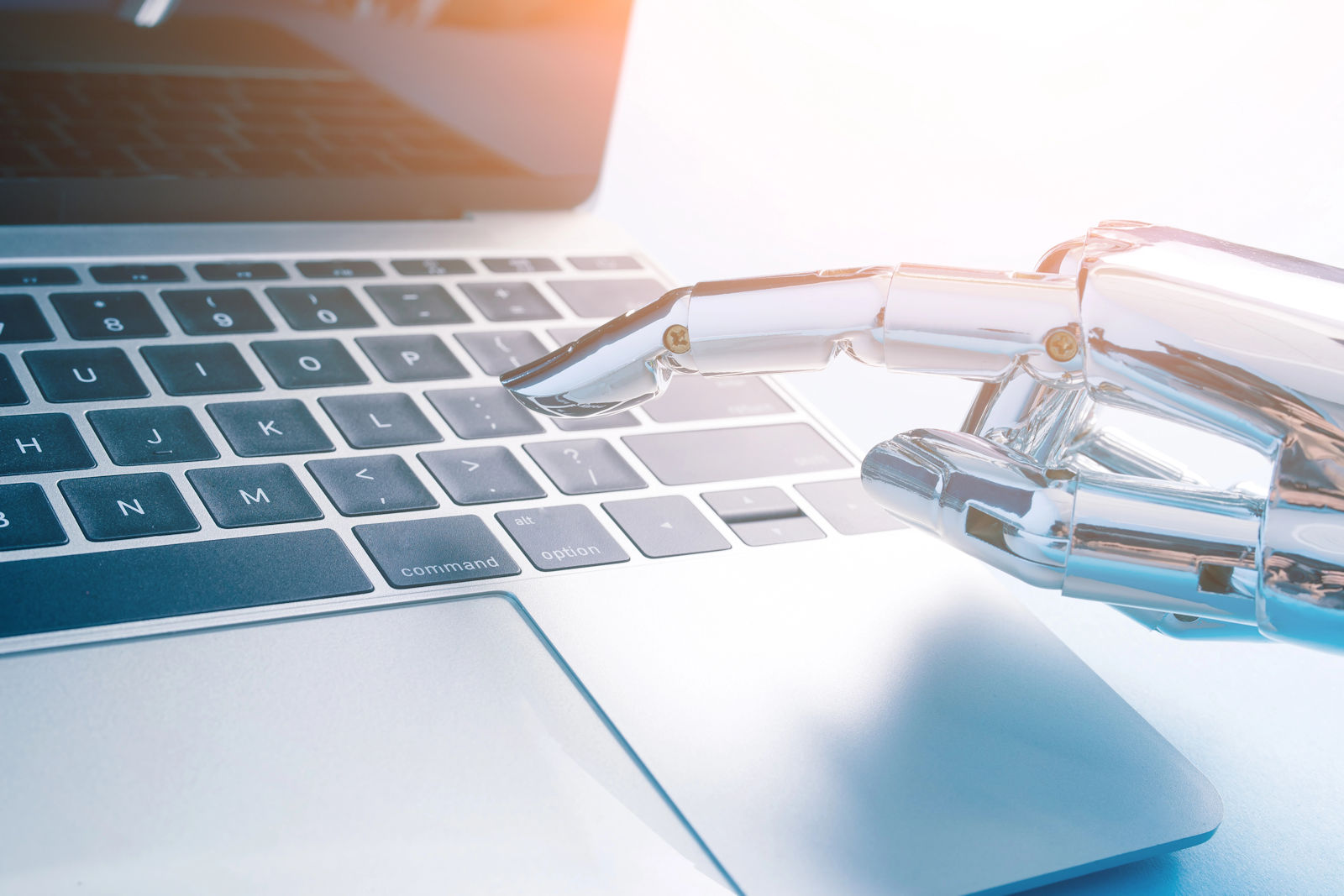 Robot hand pressing keys on laptop