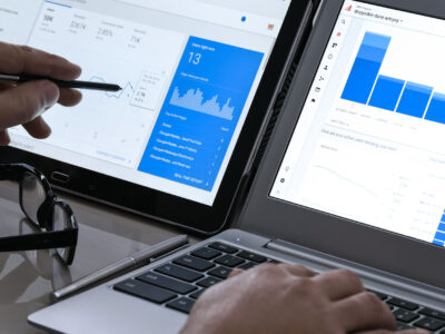 Businessman using Google Analytics in the office on the touch screen of his tablet and laptop