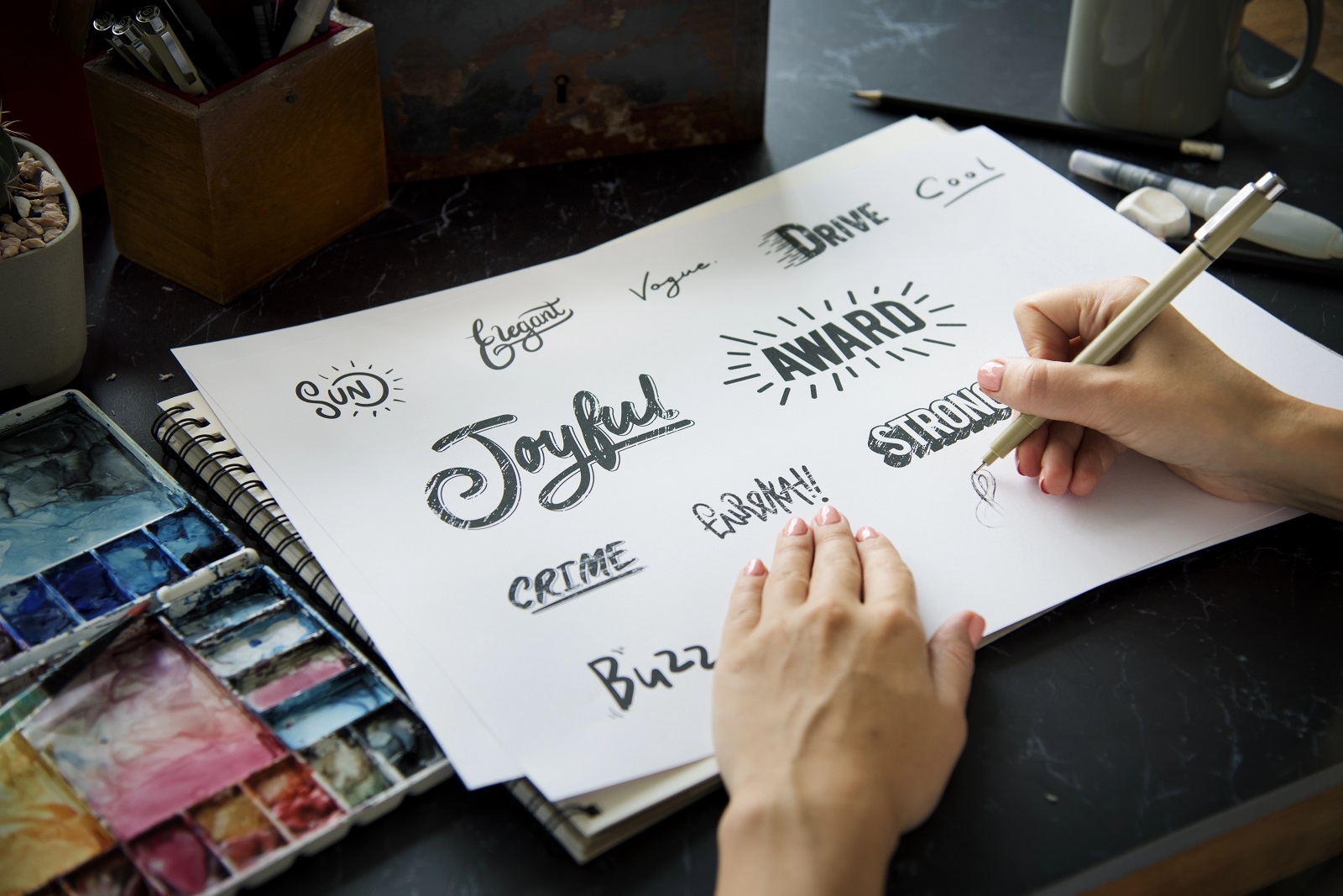 Artist using a pen drawing fonts for logos on paper