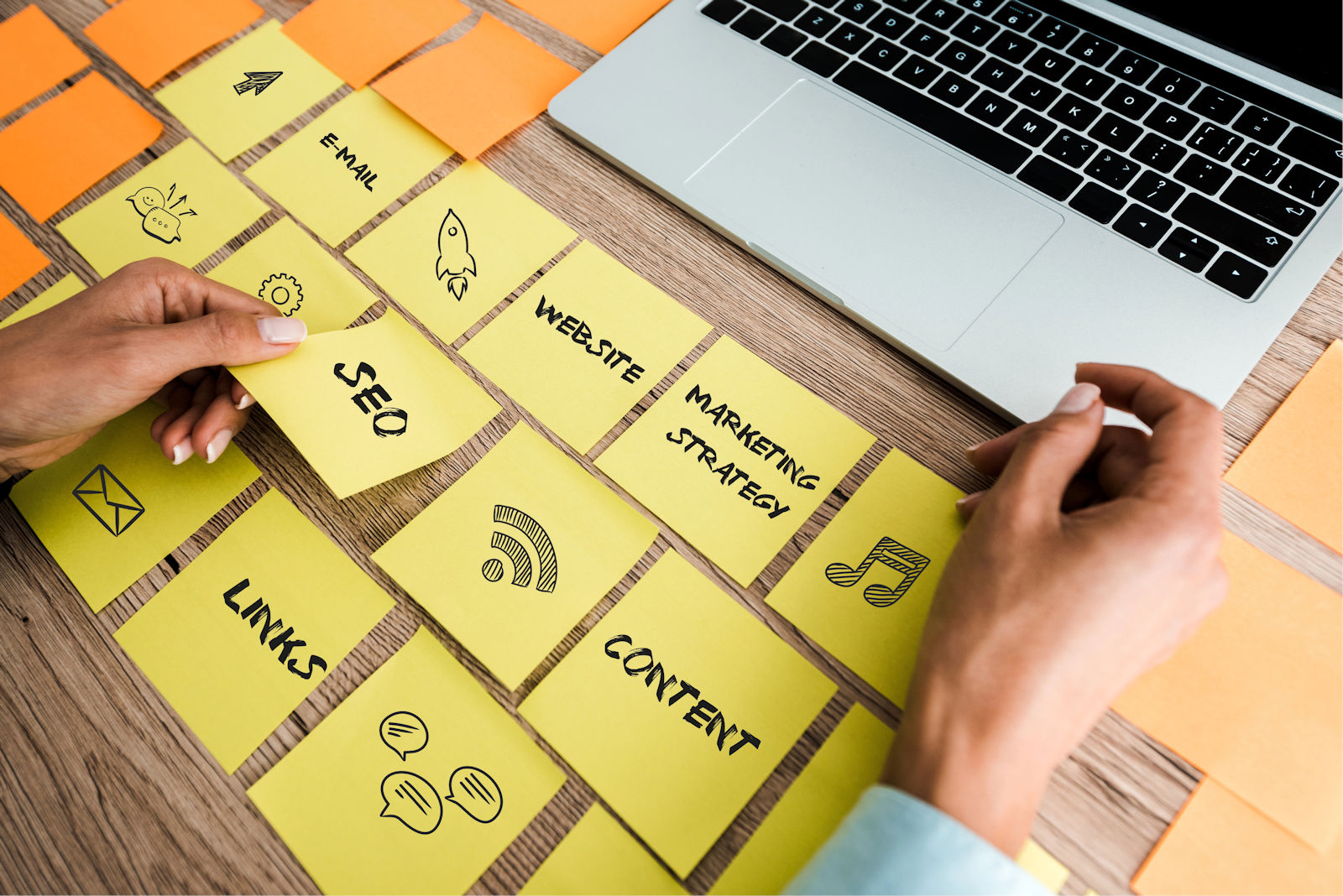 Woman touching sticky note with seo lettering near laptop on desk