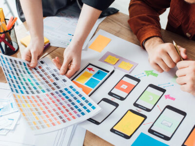 Designers planning user experience design with color palette and website sketches on table