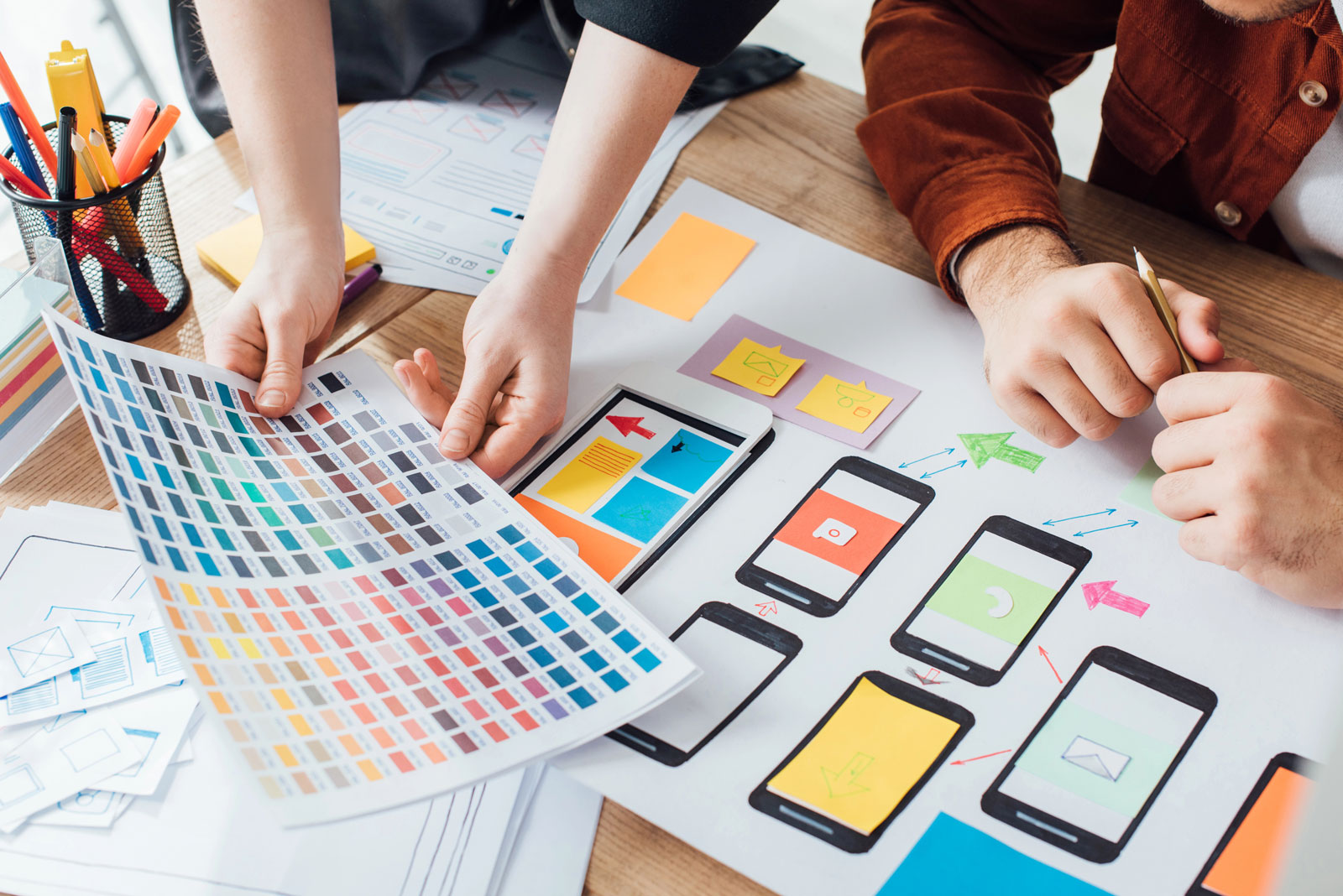 Designers planning user experience design with color palette and website sketches on table
