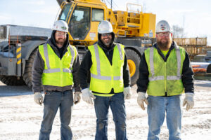 smiling construction workers next to crane