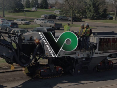 Paving company workers with Valley Paving logo in foreground