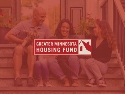 Greater Minnesota Housing Fund logo with family on steps in front of home in background