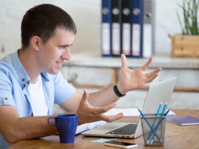 Young frustrated man in office looking at laptop computer