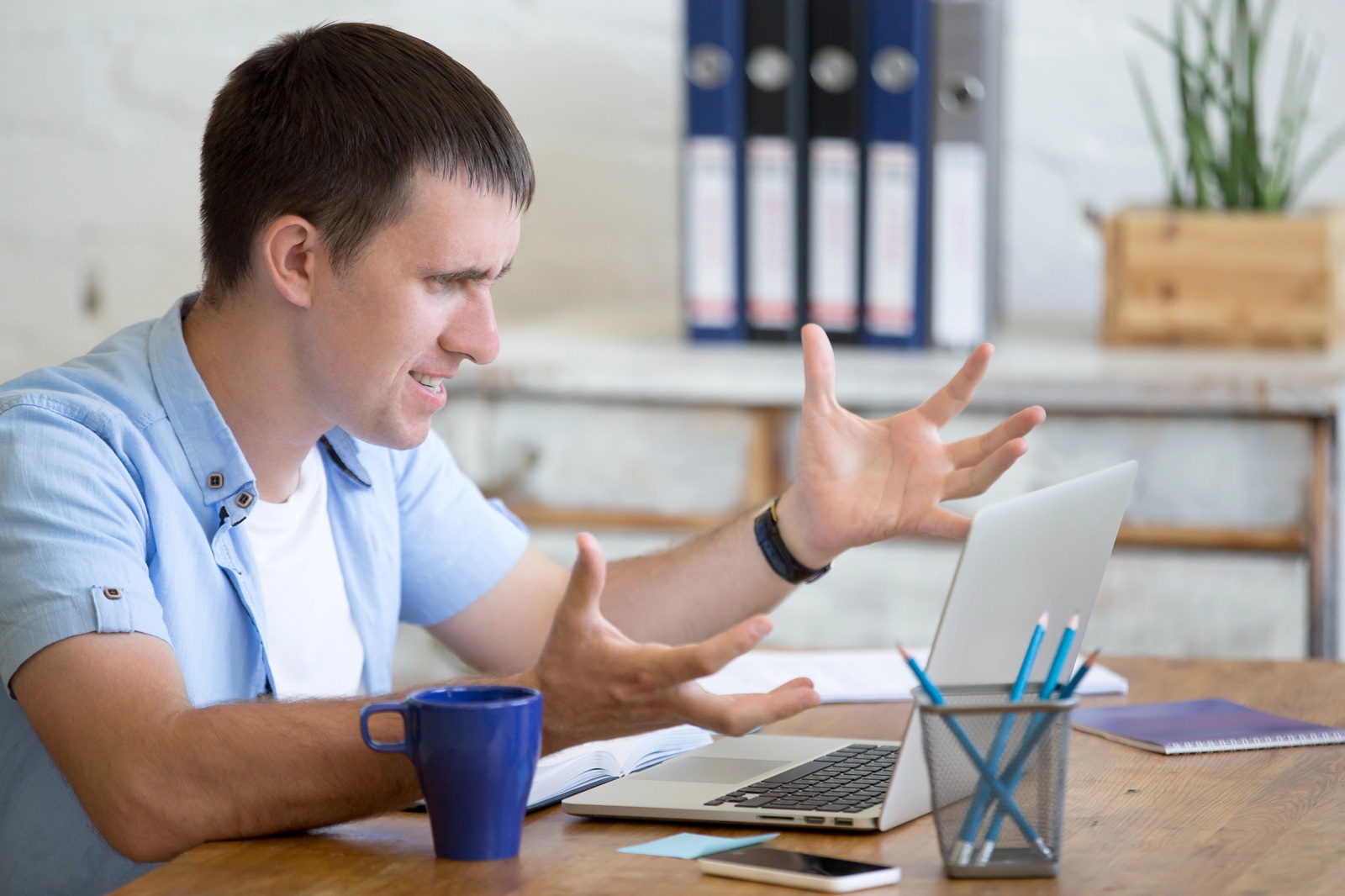 Young frustrated man in office looking at laptop computer