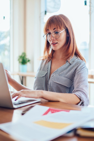 Woman wearing glasses looking at computer while auditing website